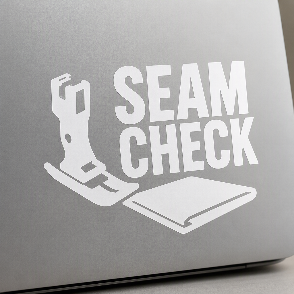 SEAM CHECK appears in bold white lettering beside a stout sewing-machine presser foot and broad folded fabric corner.