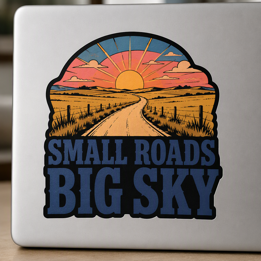 “SMALL ROADS BIG SKY” stands out in expansive indigo slab lettering beneath a rolling Kansas prairie road and broad warm sunset.