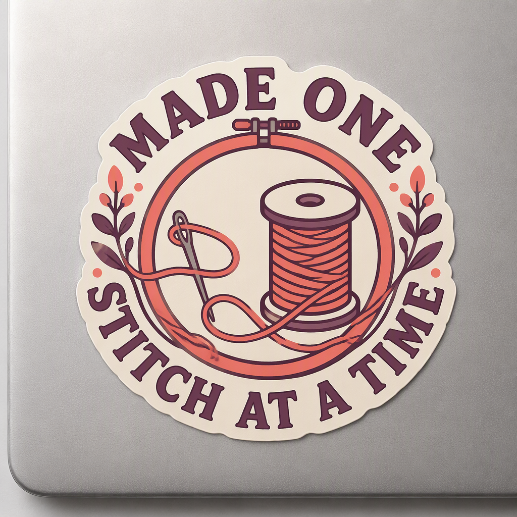 “MADE ONE STITCH AT A TIME” surrounds a wide embroidery hoop and simple thread spool, accented with floral artwork in a cheerful crafting-inspired design.